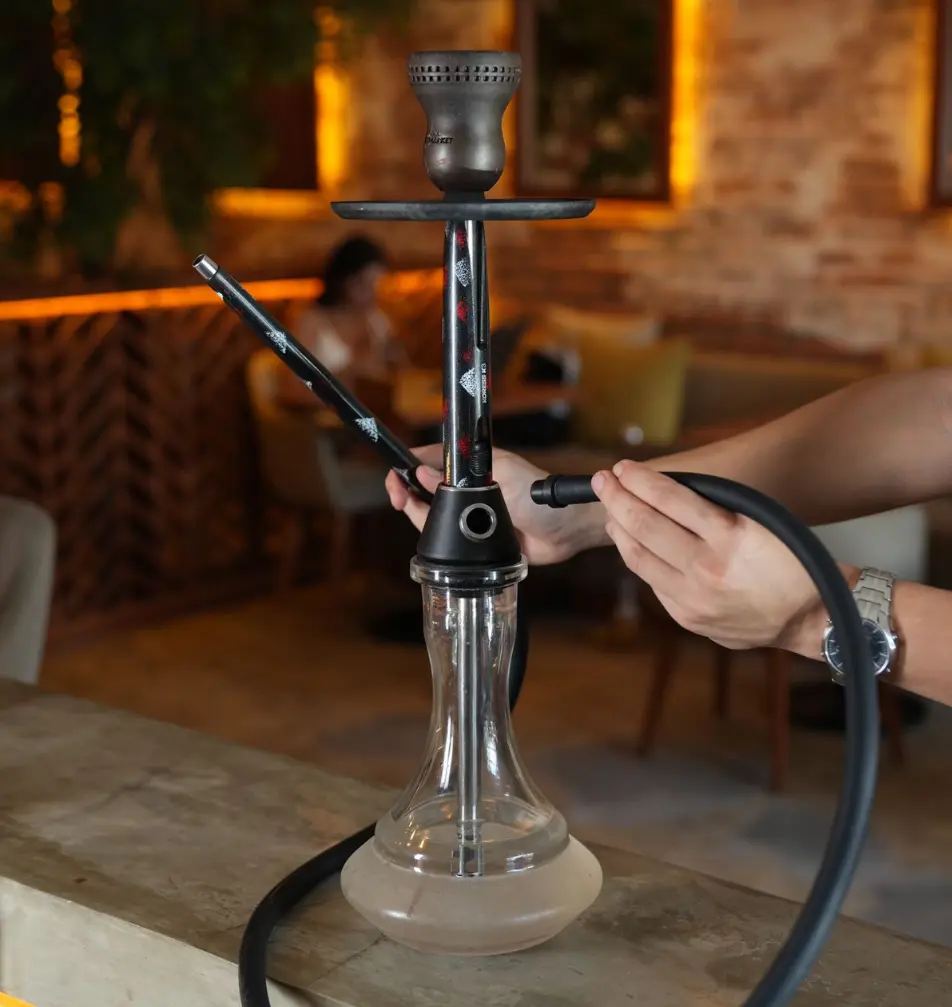 Someone easily attaching a washable silicone hose to a modern metal pipe stem, proving how incredibly simple the setup is when you are first time trying hookah at your villa.