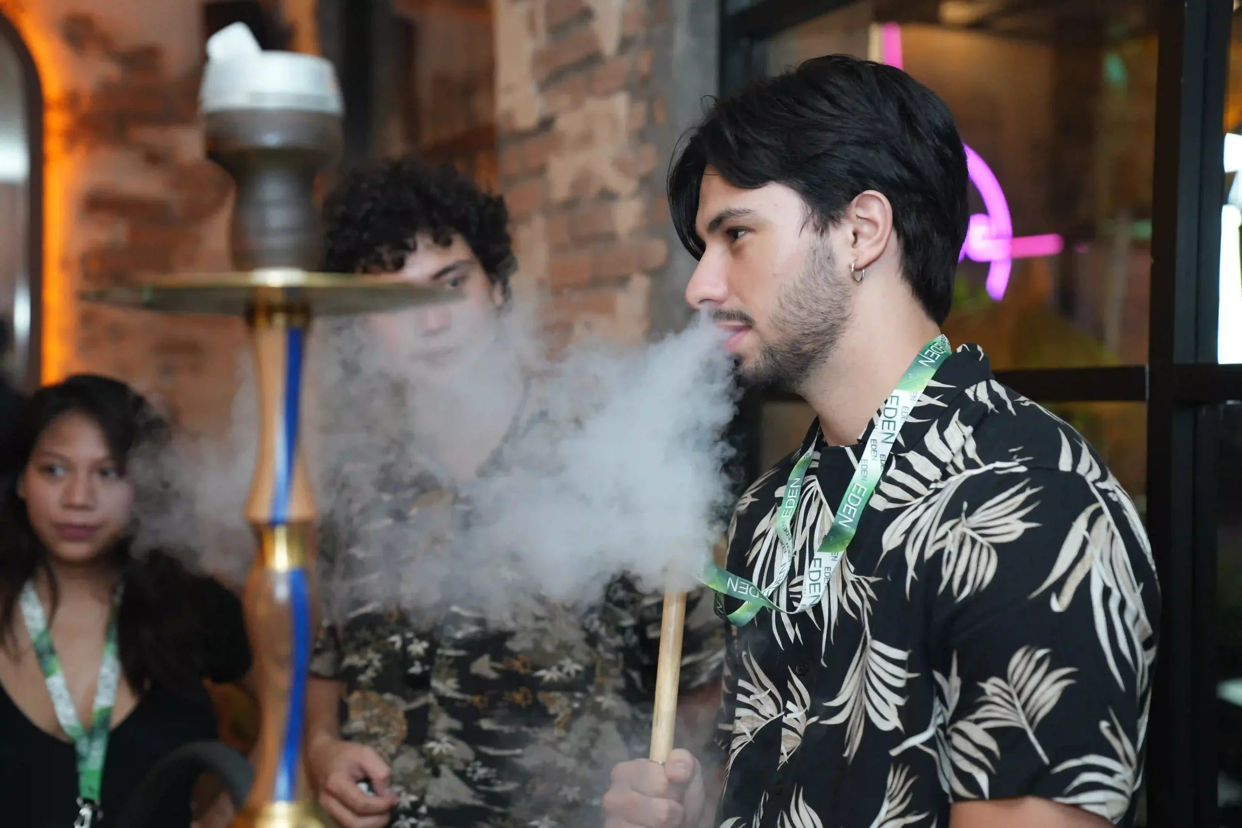 A guy enjoying a smooth, flavorful session and blowing thick smoke, showing exactly what a great experience looks like when you are first time trying hookah with friends.