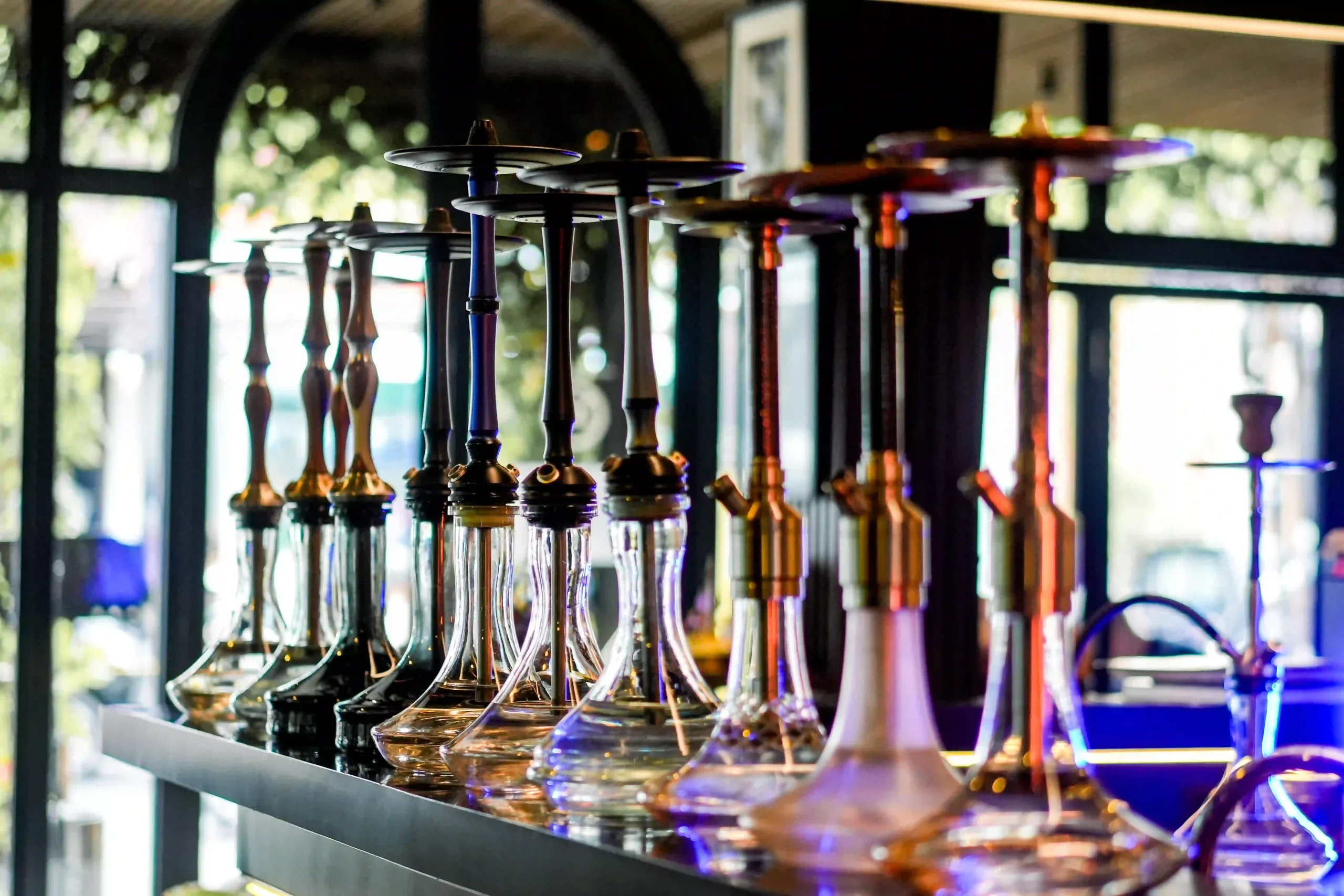 A beautiful lineup of modern glass shisha pipes on a counter, showcasing the perfect gear for anyone who is first time trying hookah at home.